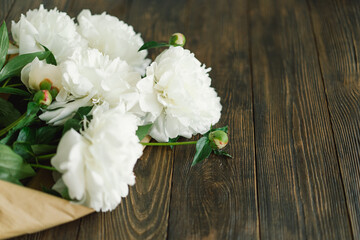 Bouquet of beautiful white peonies on wood background. Stylish floral greetings. Mothers day