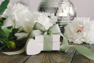 Bouquet of beautiful white peonies with gift boxes on wood background. Stylish floral greetings. Mothers day