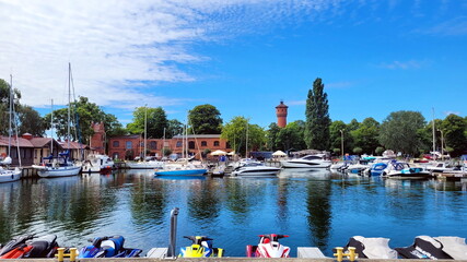 
view of the pier, port with yachts, boats, jet skis for recreation in the summer. sky and sea, combined with a red brick building and a lighthouse