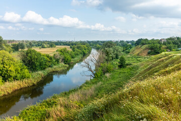 Scenic view from the hill to the landscape of a river valley with meadow and trees. Nature of Ukraine on a summer day