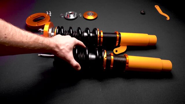 tuning car suspension, coilovers, shock absorbers and front springs in yellow and gold color for a sports drift car on a dark background assembly by the hands of a car mechanic