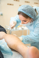 Dermatologist surgeon stitching up a wound after skin surgery, operation process