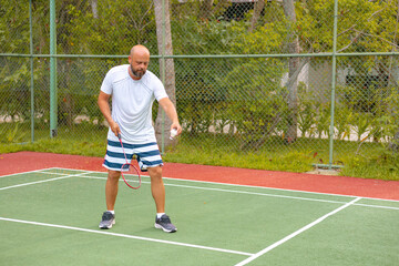 man plays badminton outdoors in the fresh air, throws a shuttlecock and holds a racket, an island in the Maldives, active recreation and sports