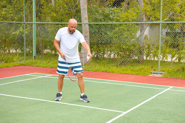 man plays badminton outdoors in the fresh air, throws a shuttlecock and holds a racket, an island in the Maldives, active recreation and sports