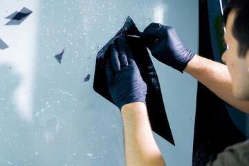 the mechanic cuts off excess pieces of tinting protective film with a clerical knife detailing