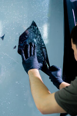 the mechanic cuts off excess pieces of tinting protective film with a clerical knife detailing