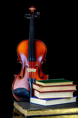 Violin with Old Books on a Reflective Black Surface and Black Background