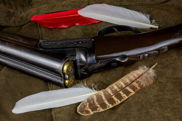 Vintage Shotgun with Assorted Feathers on an Outdoor Field Coat - 723868769