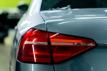 close-up of the rear red light of a beautiful expensive gray car at a detailing station