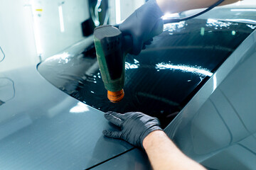 close-up, the master applies a protective film for tinting to the glass dries it car detailing