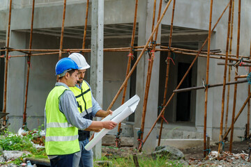 Construction contractor and foreman standing and looking at construction plans Inside the housing construction project