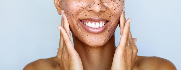 Facial granule scrub and massage. Skin care beauty portrait. Young happy woman is applying peeling...