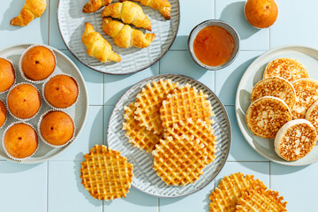 Assortment of sweets for breakfast, pancakes, muffins, waffles. Top view. Tiled background, hard light.