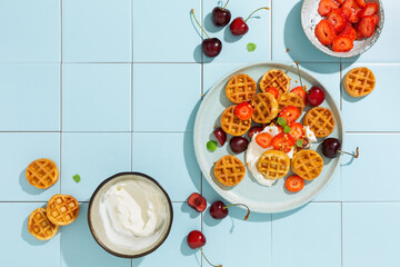 Mini waffles and fresh berries, strawberries and cherries. Sweet breakfast. Top view.