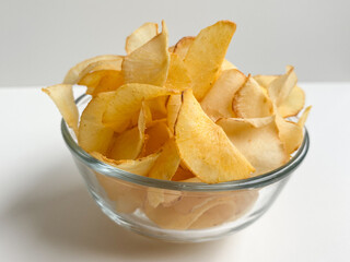 Cassava chips, in a transparent bowl, isolated in white background