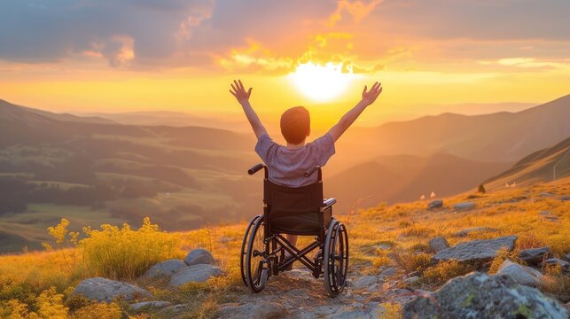 boy with raised hands up sitting on a wheelchair and enjoying sunset with mountains in the background. - Powered by Adobe