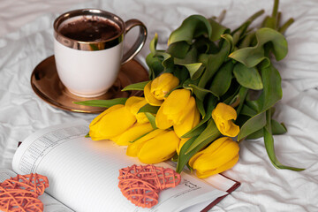 Morning, coffee and tulips. On a white bed. Romance.