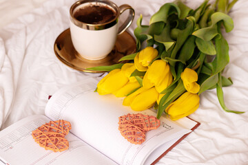 Morning, coffee and tulips. On a white bed. Romance.