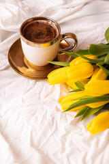 Morning, coffee and tulips. On a white bed. Romance.