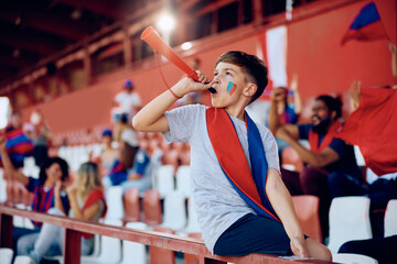 Kid blowing a vuvuzela during sports match at the stadium.