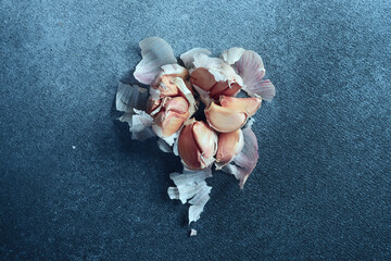 Overhead View of Garlic Cloves on Textured Blue Surface. Garlic cloves loosely arranged on a dark...