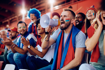 Sports fan shouting through megaphone during match at stadium.