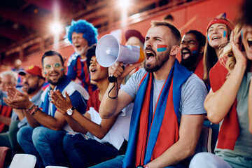 Obraz premium Sports fan shouting through megaphone during match at stadium.
