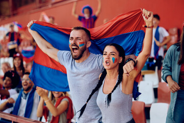 Passionate sports fans shouting during match at stadium.