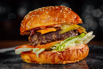 A big mouth-watering burger on a dark background
