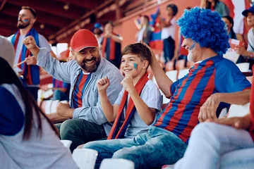 Foto op Plexiglas Happy kid cheering with his father and grandfather during sports game at stadium. © Drazen