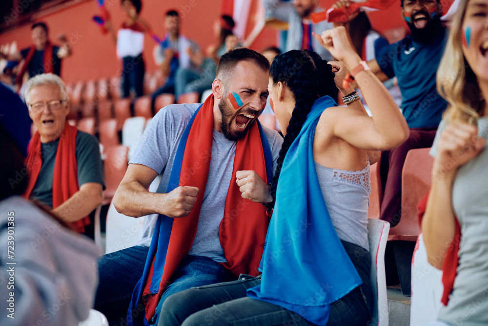 Wall mural Excited couple of sports fans shouting after winning goal of their favorite team.