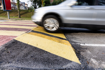 Car slowing down at speed bump or road hump painted in yellow and black stripe. Motion blur...