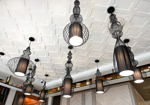A group of various chandeliers made of fine wire hanging from the ceiling for interior decoration