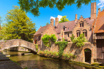 Obraz premium Quaint stone pedestrian Boniface Bridge with romantic view of canal and town, Bruges, Belgium
