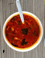Shrimp tom yum in a white bowl on a wooden table