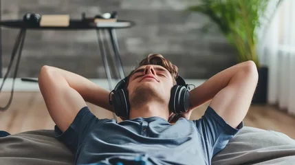 Fotobehang Teenager boy relaxing while lying in bed in headphones and listening to the music. Lost in melodies, he escapes to a world of rhythm. © Stavros