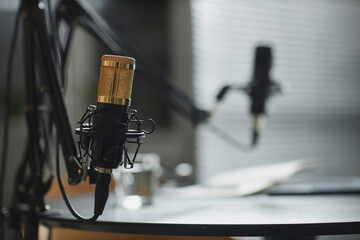 Close up shot of modern gold condenser microphone fixed on desk in professional podcast studio