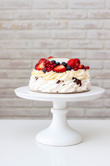 Pavlova cake with whipped cream cheese, chocolate sauce and fresh berries on grey background. Beautiful cake for the Birthday party