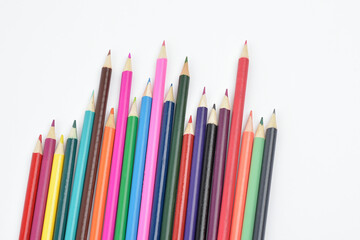 Collection of seamless coloured pencils lying loose and placed in a row facing up on white background