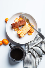 Pieces of breakfast kumquat pound cake and cup of coffee, white background.