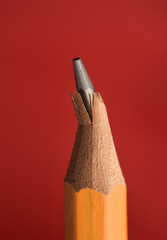 Details of broken wooden pencil tip or graphite. Isolated on red background. Broken object as a visual metaphor for fracture or crack. Close Up photography.