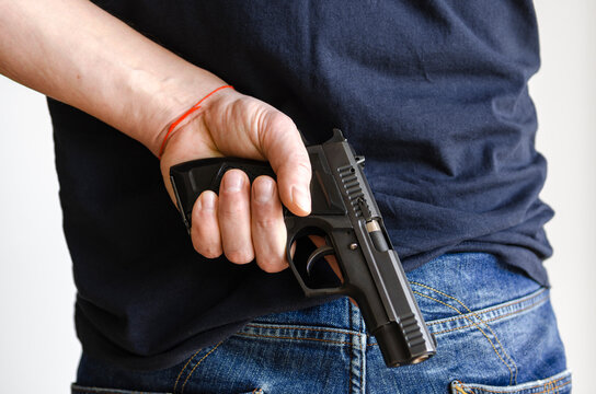Hidden Weapons. A pistol in his hand behind the man's back. Weapons in hand.