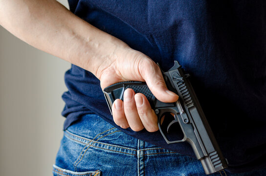 Hidden Weapons. A pistol in his hand behind the man's back. Weapons in hand.