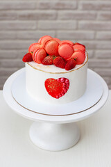 Beautiful white cake with red heart, macaroons and fresh strawberry. A sweet gift for Valentine day or for Wedding Celebration