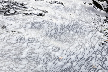 texture of water flowing in a small river, natural background. abstract background of dark water in a mountain stream close-up. abstract background of water and foam on the surface of the river