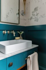 Small bathroom with a bold teal half-wall and neutral wallpaper .