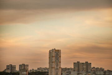 Turquoise sky between clouds over the houses of a modern city at sunset