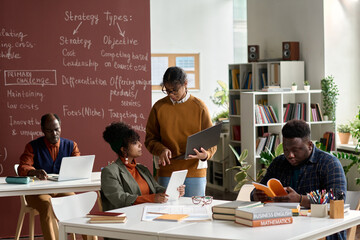 Group of African American college students working together in college classroom copy space