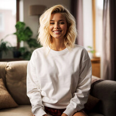 White Sweatshirt Mockup Template with a Beautiful Young Blondie Woman Posing in a Cozy Living Room. Trendy Lifestyle Photography Design. Perfect for Online Shops, Portfolios and Social Media Marketing