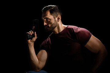 Young bearded man with gun acting like a spy or secret agent, Dark elegance: A striking low-key portrait of a young man with a beard